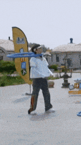 a man is holding a blue frisbee in front of a yellow flag that says ' a ' on it