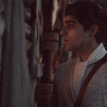 a man wearing a white shirt and brown suspenders is standing in a dark room