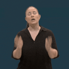 a woman in a black shirt is making a funny face with her hands up