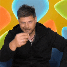 a man in a black jacket is pointing his finger