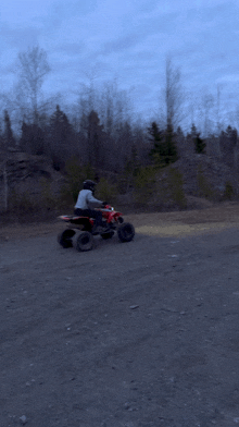 a person is riding a red atv down a dirt road