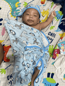 a baby is wrapped in a blue blanket that says hello dino on it
