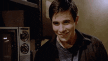 a man in a black shirt is smiling in front of a microwave that has the number 10 on it