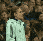 a woman in a white adidas jacket stands in front of a crowd
