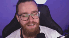 a man with glasses and a beard is sitting in a chair
