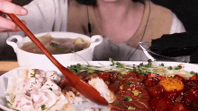 a woman is eating a plate of food with a wooden spoon .