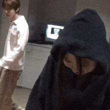 a woman wearing a black hoodie is standing next to a man wearing a white shirt