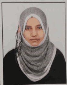 a woman wearing a hijab and a black shirt is standing in front of a white background .