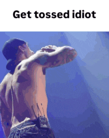a shirtless man is standing on a stage with the words get tossed idiot below him
