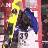 a person wearing a number 39 jersey is holding a snowboard