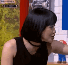a woman with short black hair is wearing a black tank top and choker necklace .