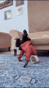 a dog wearing red pants is doing a handstand in a living room