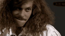 a man with long curly hair and a mustache is making a funny face