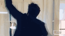 a man in a suit is standing in a room with his arms in the air .