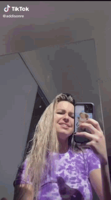 a woman is taking a selfie in the mirror with her phone .