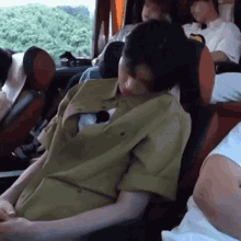 a man in a green shirt is sleeping in a car .