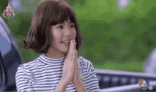 a woman wearing a wig and a striped shirt is sitting in front of a car .