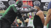 a man in a green shirt with a skull on it stands next to another man in a black shirt