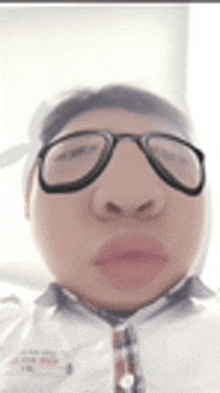 a man wearing glasses and a tie is taking a selfie .