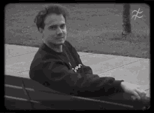 a young man is sitting on a bench in a park .
