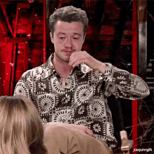 a man in a floral shirt is sitting next to a woman in a chair