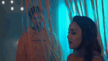 a man and a woman are standing in front of a blue curtain .