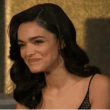 a woman in a black tank top is smiling and making a funny face