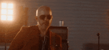a bald man is playing a bass guitar in a dark room .