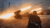 a man is standing in front of a rocket launcher that is being fired .