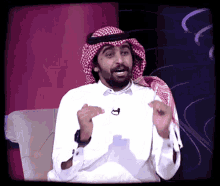 a man with a beard wearing a head scarf and a white shirt has a microphone on his neck