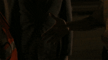 a man with a mustache in a yellow shirt stands in the dark