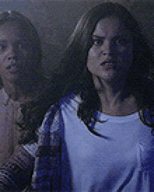 a couple of women are standing next to each other in a dark room .