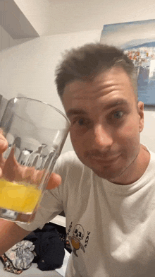 a man in a white shirt is holding a glass of orange juice in his hand
