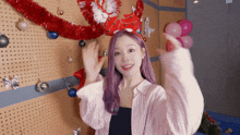 a girl with purple hair is standing in front of a christmas tree