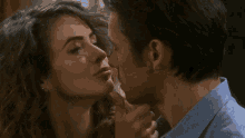 a man and a woman are kissing and the woman is touching the man 's face