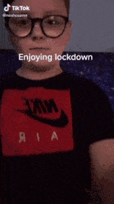 a boy wearing glasses and a nike shirt is enjoying lockdown .