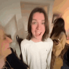 a man with long hair is making a funny face while standing next to a woman .