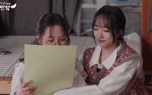 two girls are looking at a piece of paper with glow written on the bottom