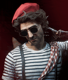 a man wearing a red beret and sunglasses has a striped shirt and suspenders around his waist