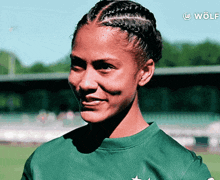 a woman wearing a green shirt with a wolf logo on the bottom
