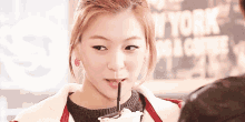 a woman drinks through a straw in front of a sign that says new york