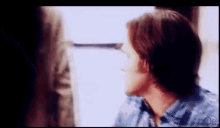 a man in a blue shirt is talking to a woman in a room .