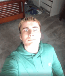 a young man wearing a green adidas sweatshirt takes a selfie