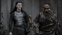 a man and an orc are standing next to each other .