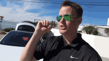 a man wearing sunglasses and a nike shirt is talking on a cell phone