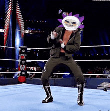 a wrestler is dancing in a wrestling ring with a mask on his head