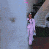 a woman in a pink outfit stands in front of a building with a sign that says " we might be famous "