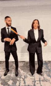 a man and a woman in suits are standing next to each other holding a bat .