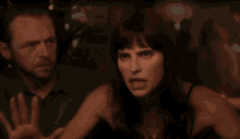 a man and a woman are standing next to each other in a dark room . the woman is making a funny face .