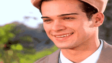 a young man wearing a hat and a suit is smiling
